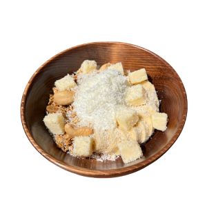 チーズキューブ、バナナ、グラノーラ、練乳がトッピングされた、プレーンヨーグルトのボウル。