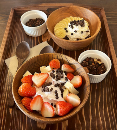 いちご、チーズキューブ、チョコレートキューブがトッピングされたギリシャヨーグルトのボウルの写真。