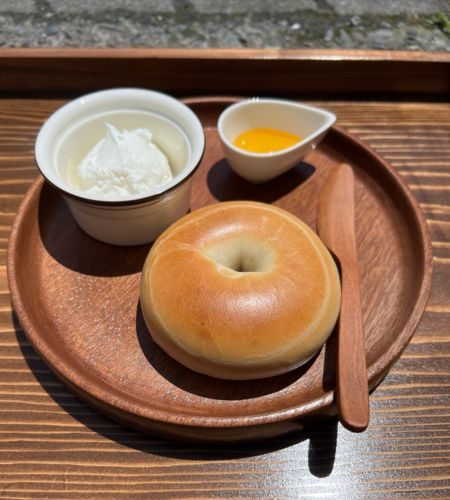 スライスしたベーグルにクリーミーなギリシャヨーグルトと新鮮なベリーをトッピングした写真。